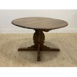 Ercol, a stained elm extending dining table, the oval top with additional leaf raised on a cruciform