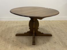 Ercol, a stained elm extending dining table, the oval top with additional leaf raised on a cruciform