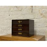 An Edwardian stained and lacquered mahogany table top chest fitted with four drawers having gilt