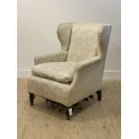 A late Victorian wing back chair, upholstered in ivory damask, raised on turned front supports