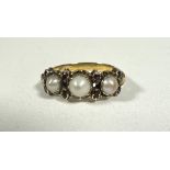 An Edwardian yellow metal set three graduated cultured pearls separated by four pairs of pink