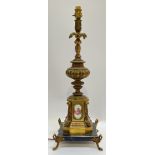 A large Rococo style gilt metal and porcelain lamp on marble base, the porcelain plaques decorated
