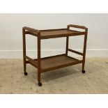 A mid century teak drinks trolley, the two tiers on turned supports moving on castors H66cm,