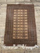A hand knotted Turkoman style rug, the brown ground with lozenge design enclosed by a border with