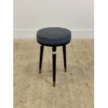 A mid century stool, circa 1970, the vinyl upholstered seat raised on three turned and tapered