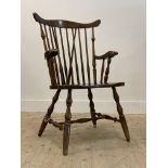 A 20th century stained beech Windsor type chair, with comb back, open arms, saddle seat, raised on