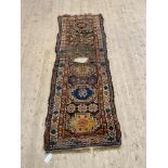 An antique hand knotted Caucasian runner rug, the brown ground with multiple guls and bordered 300cm