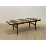 A mid century teak coffee table, the top inset with ceramic tiles depicting stylised flower head