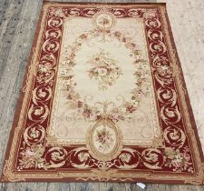 A French Aubusson style rug, the beige ground with vining roses within a claret border having