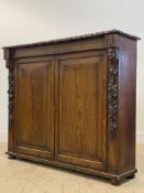 A Victorian oak side cabinet, the floral moulded top above two panelled doors enclosing shelves,