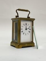 A Late 19th century brass carriage time piece clock, the case with swing handle above a bevelled