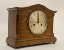 An Edwardian oak mantel clock, the case with chequered inlay and standing on brass ball supports,