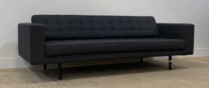 A contemporary three seat sofa upholstered in buttoned grey wool, raised on tubular supports