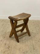 A rustic carved and adzed elm stool in the manner of Tim Stead, the dished top raised on a jointed