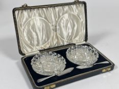 A case containing a pair of crystal slice cut butter dishes and a pair of Birmingham silver butter