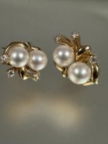 A pair of yellow metal twin cultured pearl earrings set in scroll and three diamond points