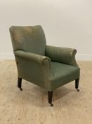 An Edwardian easy chair, the arms, back and seat covered in green fabric with horse hair stuffing,