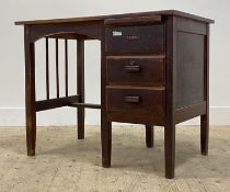A 1940's stained oak desk, the rectagular top above a brushing slide and three drawers, raised on