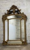 An impressive gilt framed mirror in the baroque taste, profuesely decorated with urns, cherubs and