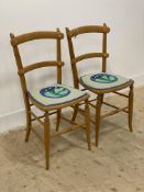 A pair of Edwardian beech side chairs, with twin rail back over upholstered seat panel, raised on