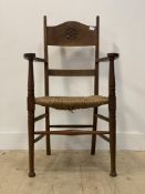 An Arts and Crafts period country oak elbow chair, the shaped crest rail carved with lattice