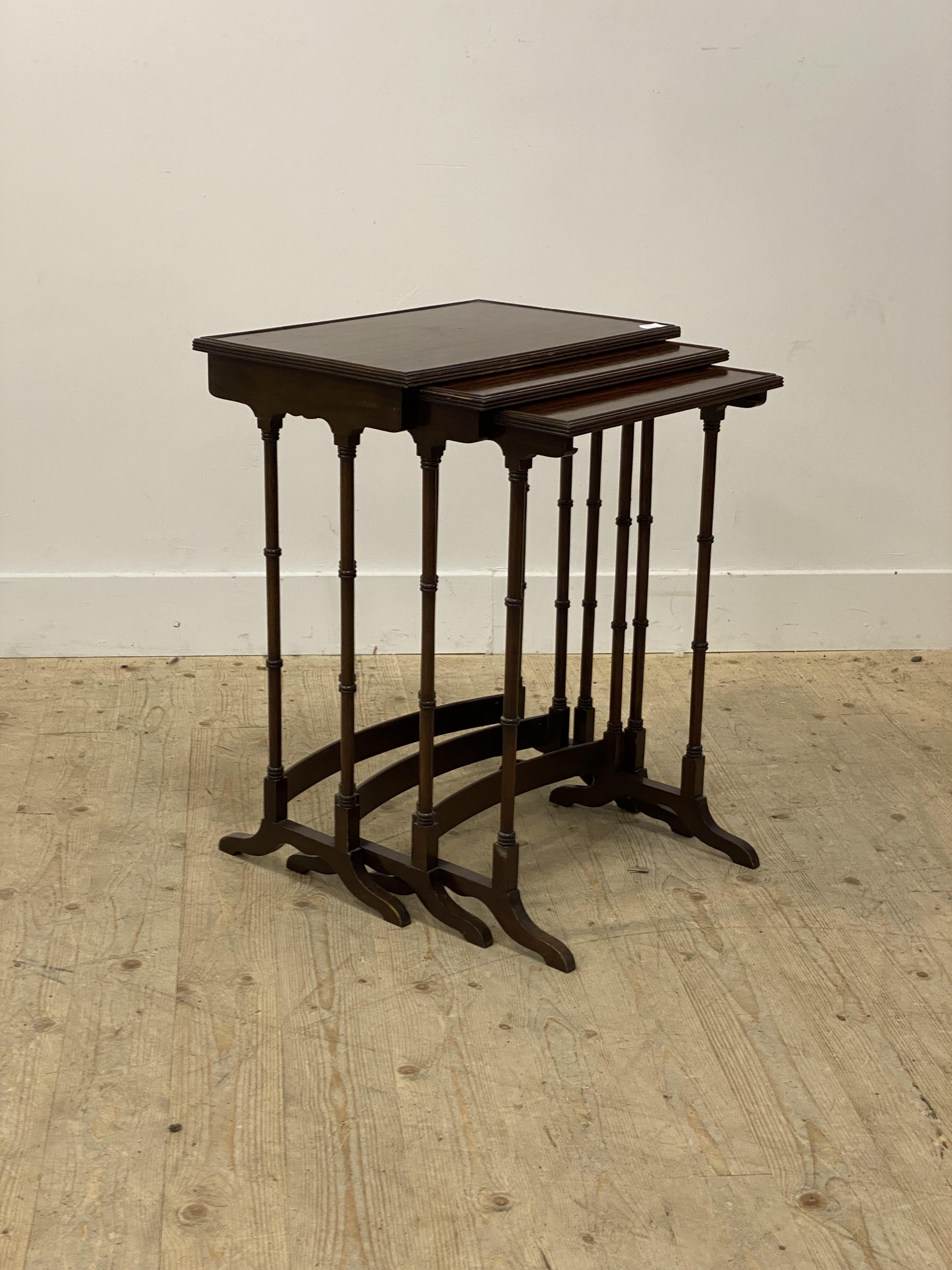 An Edwardian mahogany nest of three tables, each top with a reeded edge and raised on slender ring