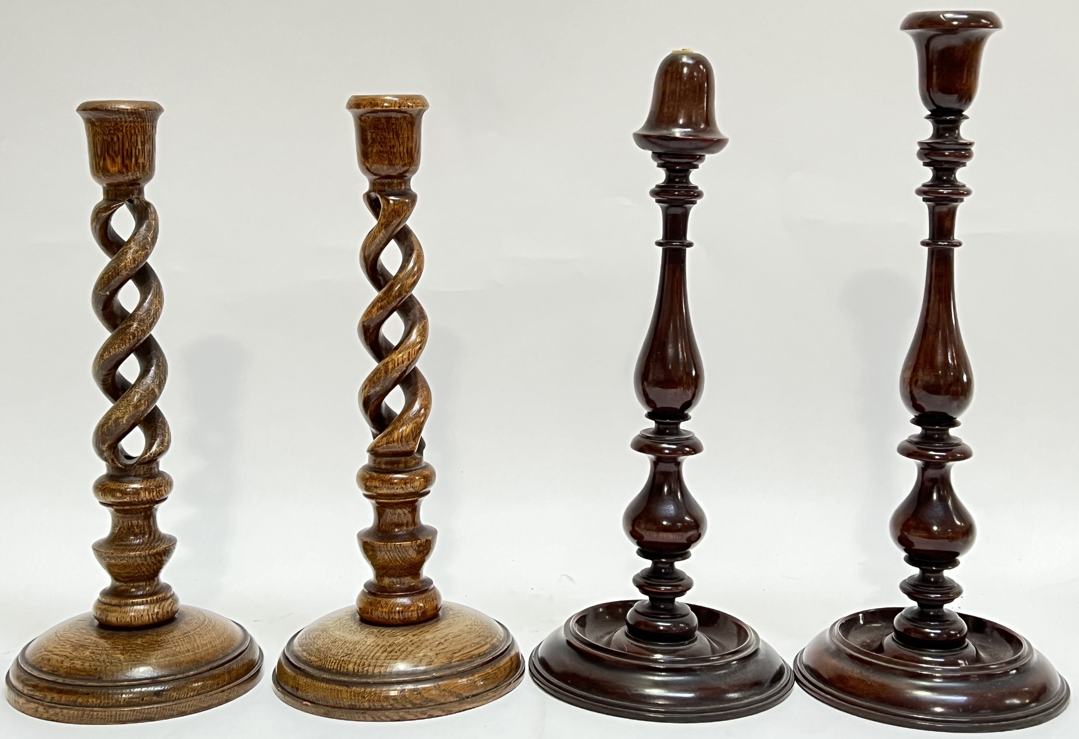 A pair of twist-stem oak candlestick holders (h- 31cm), together with a pair of mahogany candlestick