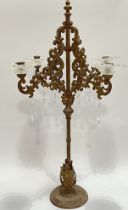 A large cast iron four-arm candelabra with glass drip pans and acrylic lustres (h- 73cm, w- 38cm)