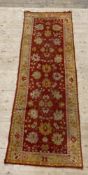 A hand knotted Ziegler type runner rug, the red field with flower head motif, and bordered 93cm x