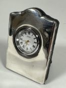 A R Carr modern silver cased quartz miniature table clock with easil stand, (H x 9cm x W x 6.5cm)