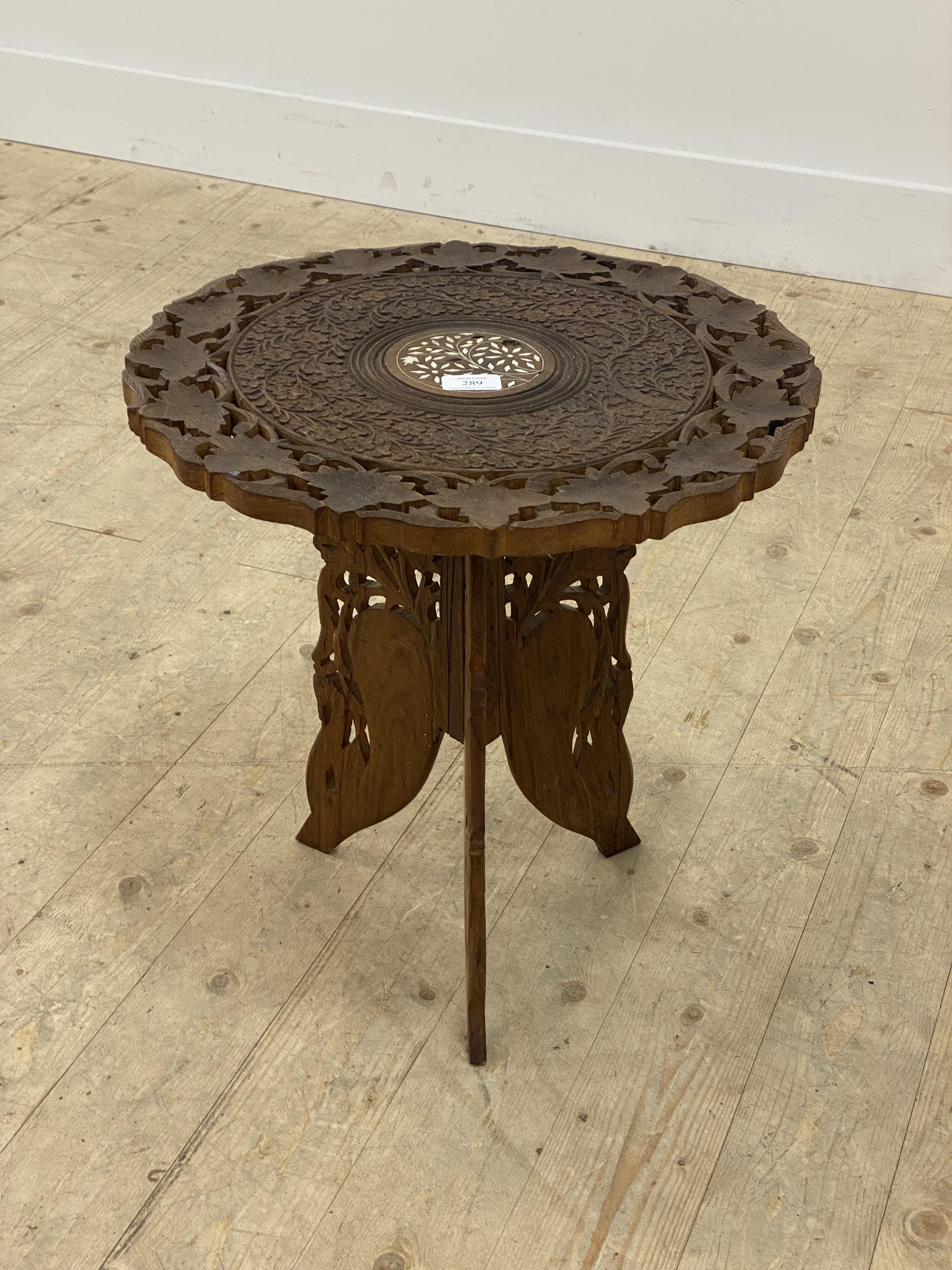An Indian carved hardwood occasional table, the octagonal top raised on three folding panel supports