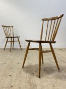 Ercol, a vintage pair of beech and elm comb back chairs, each with saddle seat raised on turned