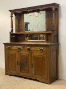 An Arts and Crafts period oak dresser, the raised back with carved pediment over two bevel glazed