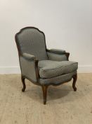 A French style beech framed bergere armchair, the moulded and scroll carved show frame enclosing