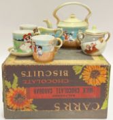 A miniature child's tea set decorated with children at play comprising three cups, two saucers, a mi