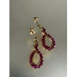 A pair of yellow metal figure of eight style drop earrings set fifteen round cut rubies, ( L x