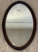 An early 20th century mahogany oval wall hanging mirror with egg and dart moulded frame enclosing