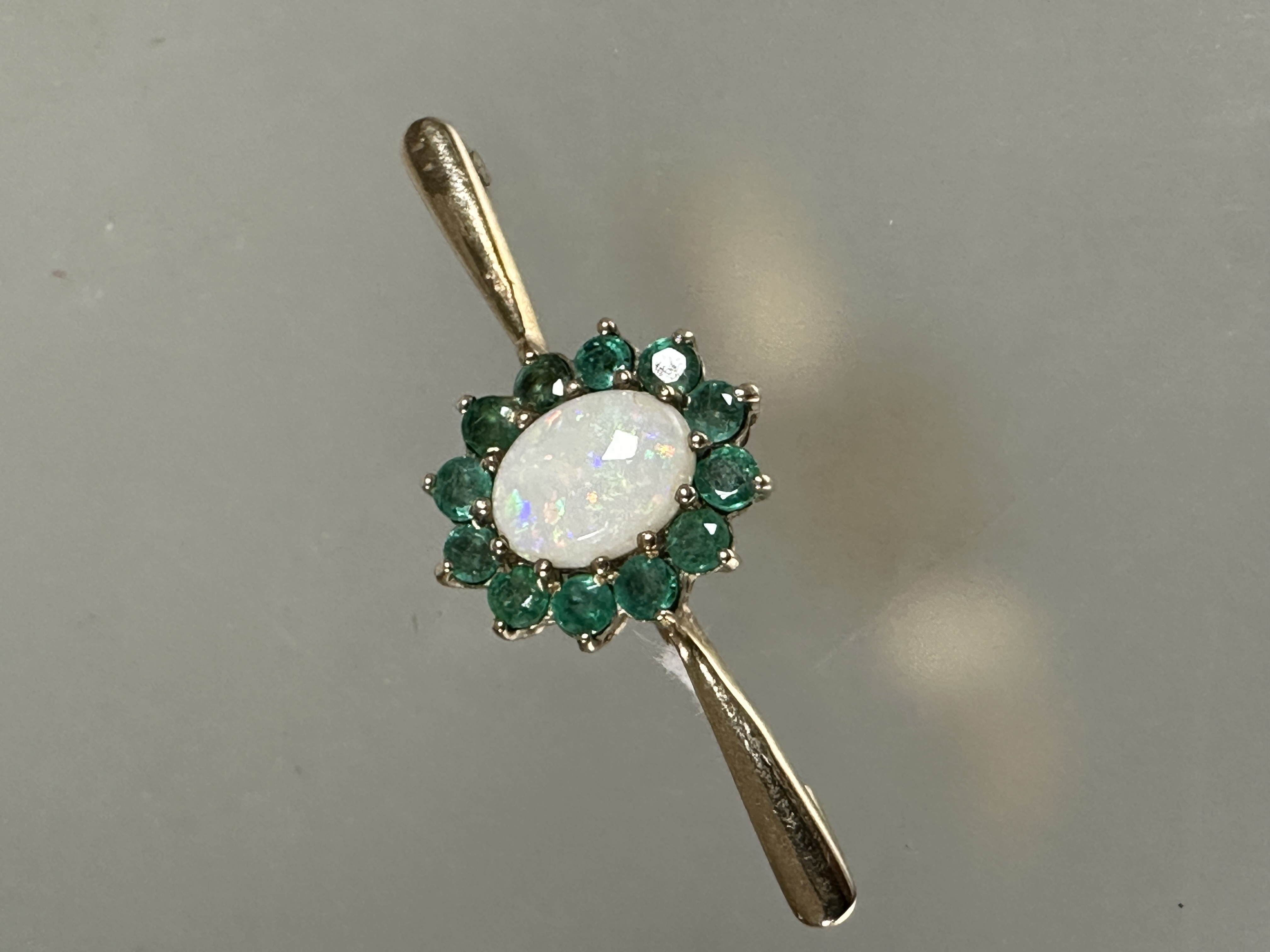 A 9ct gold water opal and emerald cluster set bar brooch, (L x 4cm x W x 1.5cm) 2.6g