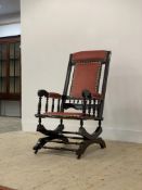 An early 20th century American style rocking chair, the stained walnut frame with upholstered seat