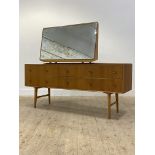 A mid century oak veneered dressing chest, the large swing mirror over six drawers, raised on