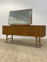 A mid century oak veneered dressing chest, the large swing mirror over six drawers, raised on