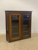 An Edwardian mahogany bookcase, the moulded top over blind fret carved frieze and two glazed doors