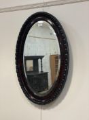 An early 20th century rosewood wall mirror of oval outline, with ebonised egg and gadroon boarder