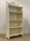 An early 20th century Arts and Crafts style white painted five height open bookcase, with serpentine