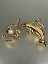 A yellow metal dolphin charm (L x 3.5cm) and a 9ct gold figure or eight style pendant set central