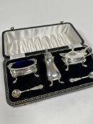 A Birmingham silver three piece condiment set comprising a baluster pepperette raised on pad feet, a