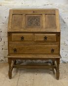 An Arts and Crafts oak bureau, early 20th century, the panelled fall front carved with floral boss