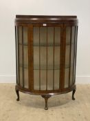 An early 20th century walnut bowfront display cabinet, the glazed door enclosing two glass