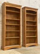 A pair of polished pine floor standing open bookcases, each fitted with five adjustable shelves.