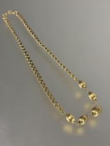 An 18ct gold triple chain link necklace mounted five oval engine turned decorated beads, one link